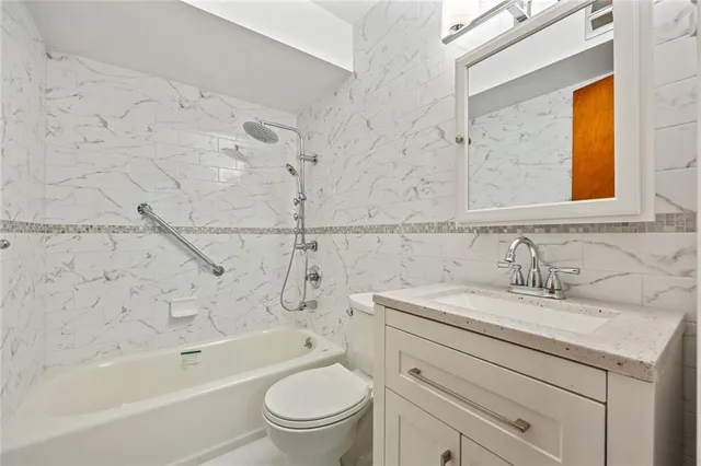 a bathroom with a granite countertop sink a toilet and bathtub