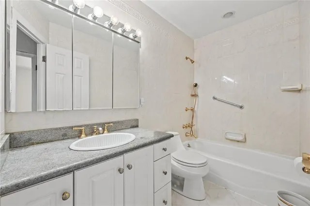 a bathroom with a granite countertop sink a toilet a mirror and shower