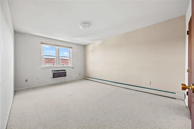 an empty room with windows and refrigerator