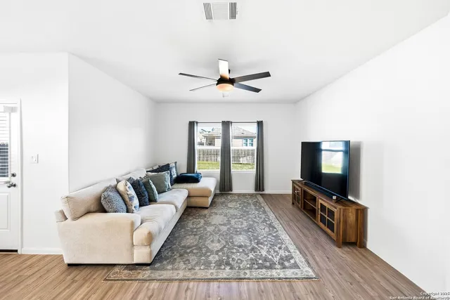 a living room with furniture a flat screen tv and a large window