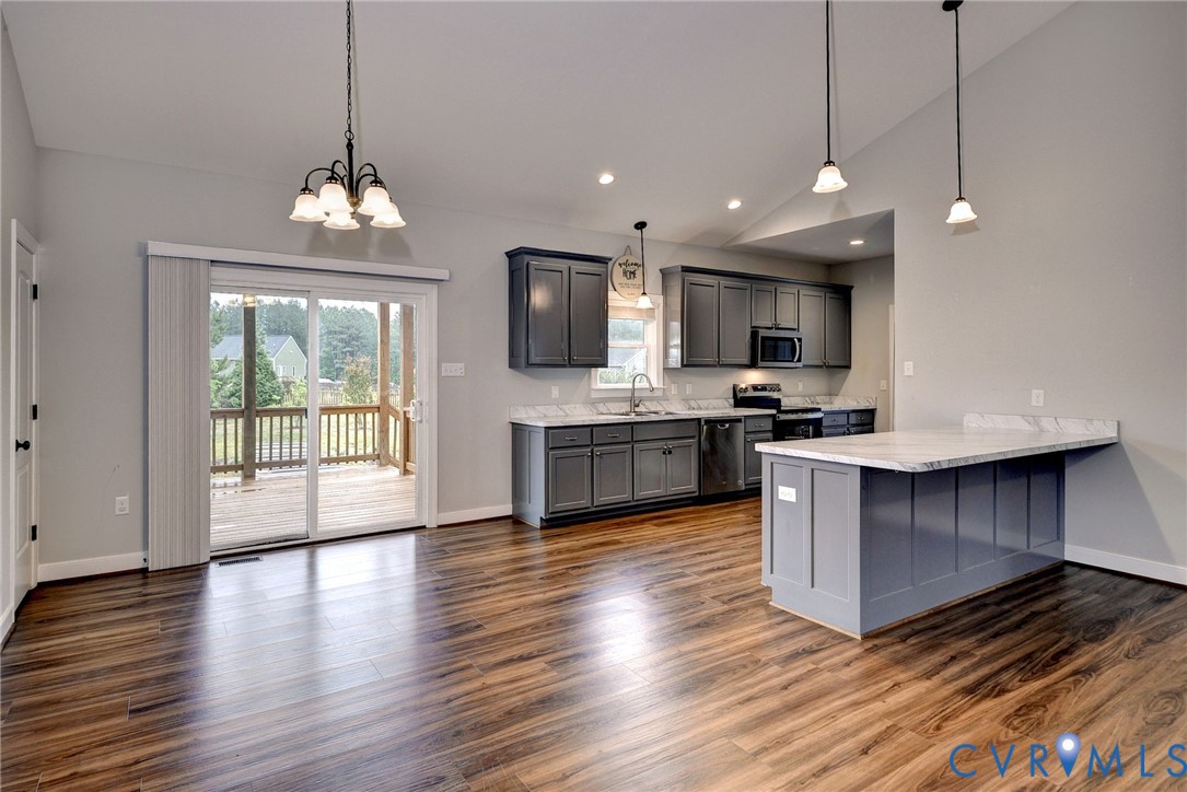 8904 Rock Cedar Road New Kent, VA 23124 - Photo 7 of 37 a large kitchen with stainless steel appliances granite countertop a stove and a wooden floor
