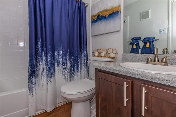 a bathroom with a granite countertop sink and a toilet