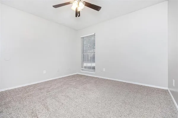 an empty room with a chandelier fan and windows