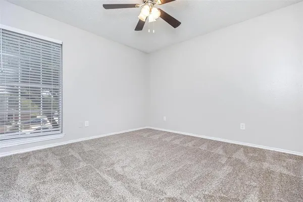 an empty room with a chandelier fan and windows