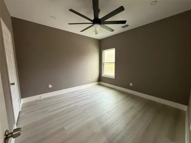 an empty room with windows and fan