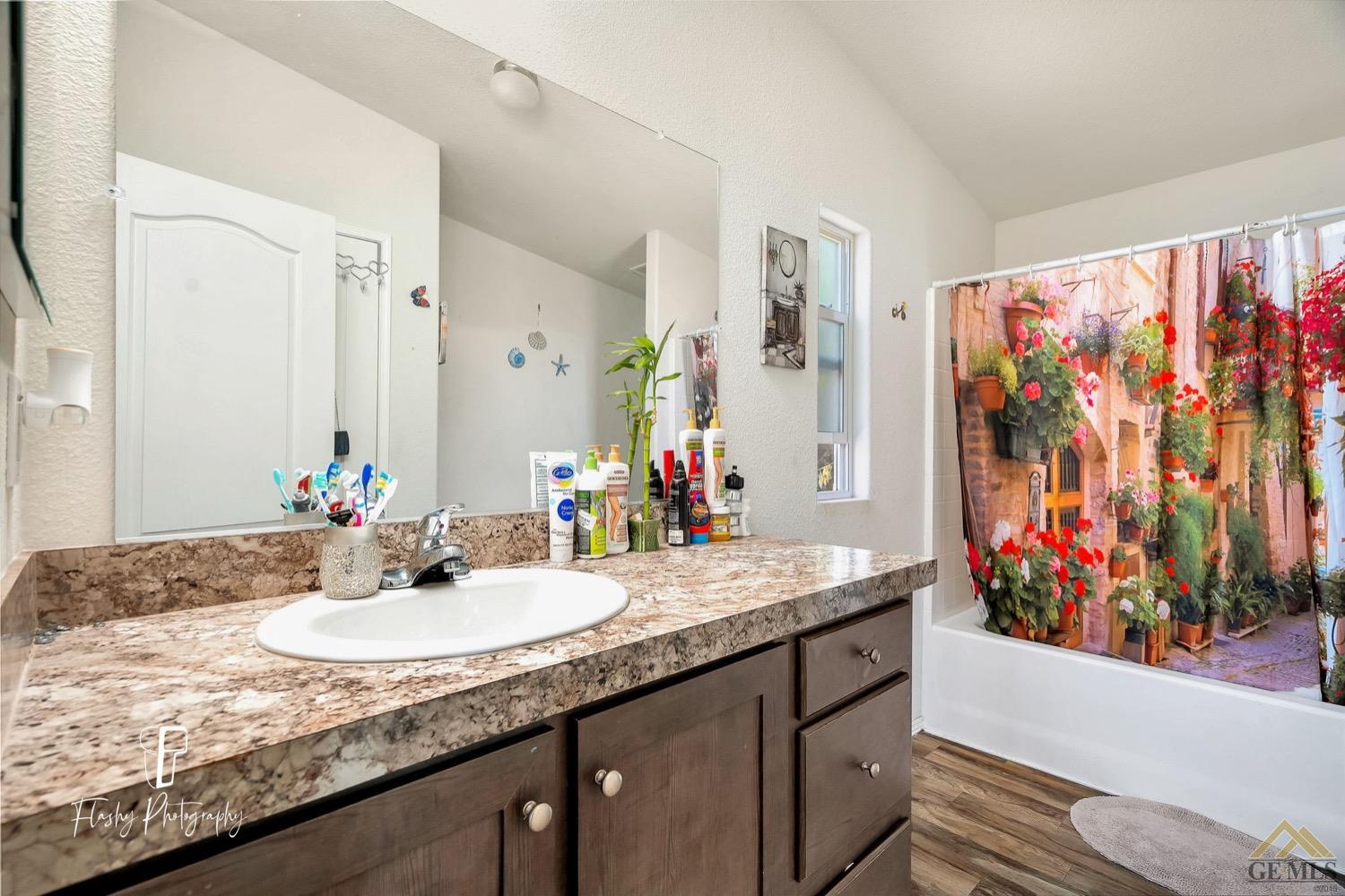 Undisclosed Address Bakersfield, CA 93308 - Photo 19 of 32 a bathroom with a granite countertop sink a mirror and a shower