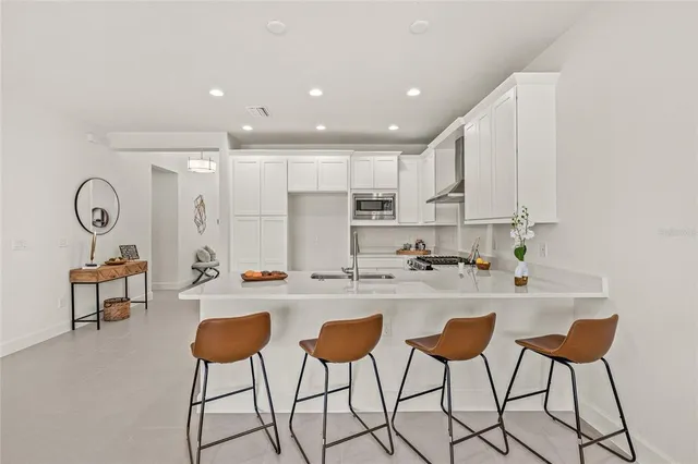 a kitchen with stainless steel appliances granite countertop a stove a refrigerator a sink and white cabinets with wooden floor