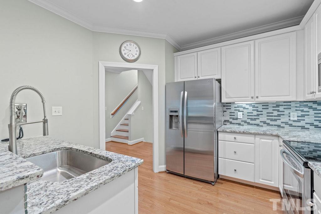 1303 Cameron View Court Raleigh, NC 27608 - Photo 7 of 30 a kitchen with granite countertop a sink and a refrigerator