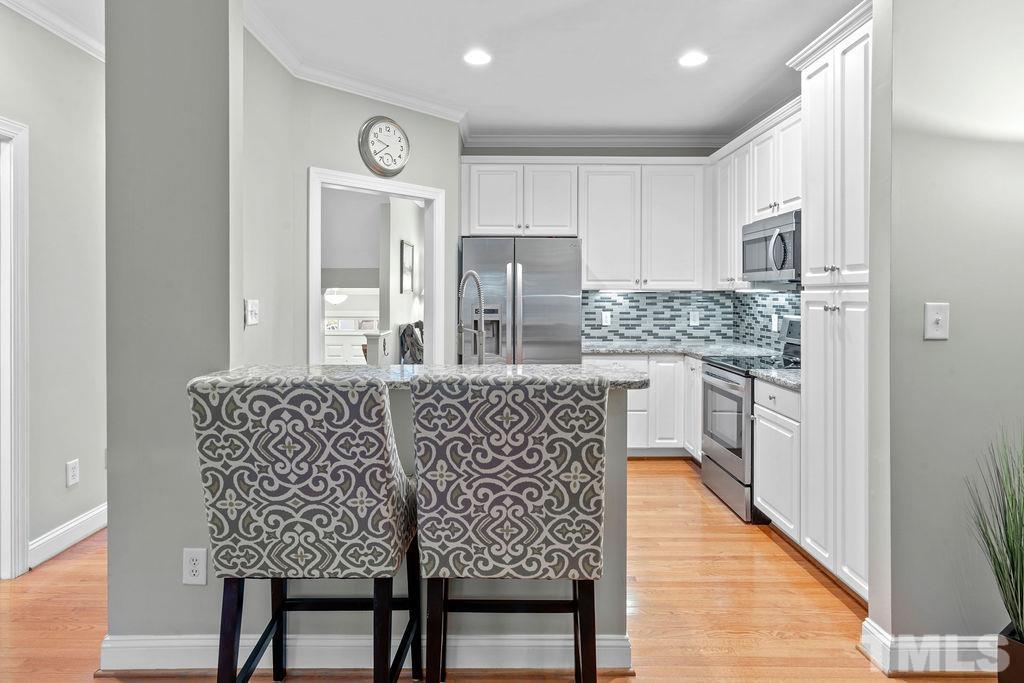 1303 Cameron View Court Raleigh, NC 27608 - Photo 8 of 30 a dining room with kitchen island stainless steel appliances furniture a large window and kitchen view