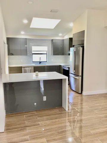 a kitchen with kitchen island a counter top space cabinets and stainless steel appliances