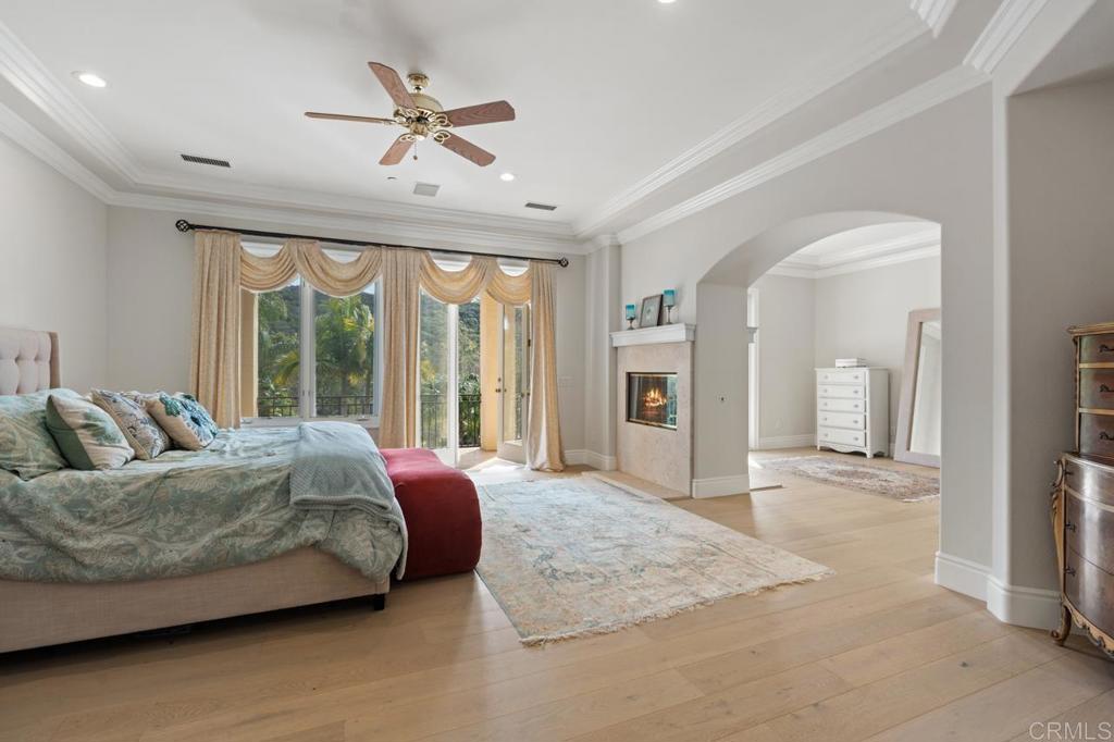 6773 Poco Lago Rancho Santa Fe, CA 92067 - Photo 35 of 65 a spacious bedroom with a large bed a chandelier and large window