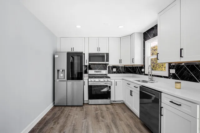 a kitchen with a sink white cabinets and stainless steel appliances
