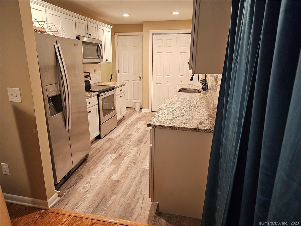 a kitchen with refrigerator a counter space and wooden floor