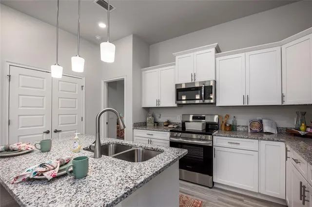 a kitchen with granite countertop a sink a stove and cabinets