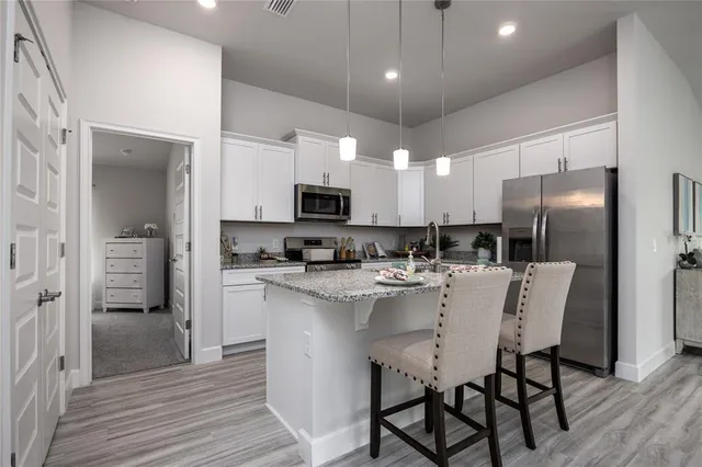 a kitchen with stainless steel appliances a refrigerator stove a sink a dining table and chairs