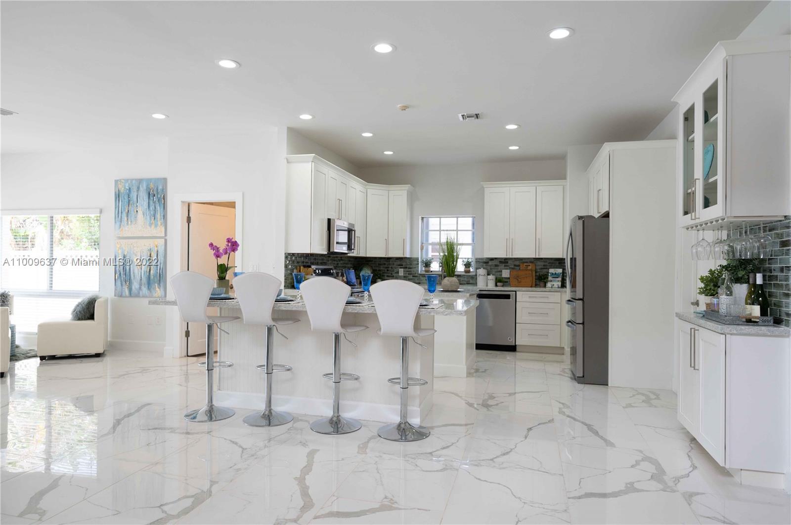 1700 Cleveland Road Miami Beach, FL 33141 - Photo 12 of 60 a kitchen with white cabinets and stainless steel appliances