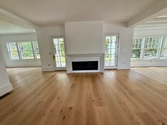 an empty room with wooden floor fireplace and windows