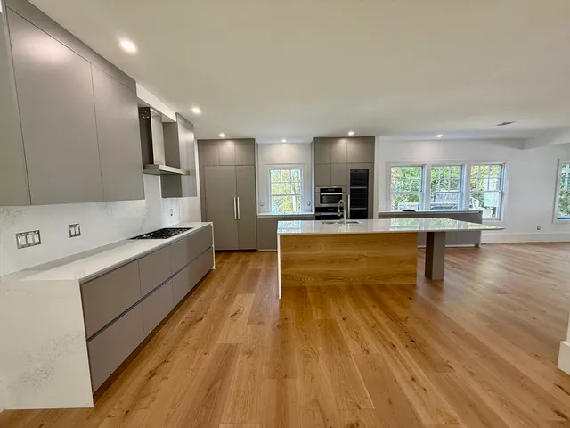 a large white kitchen with wooden floor and a large window