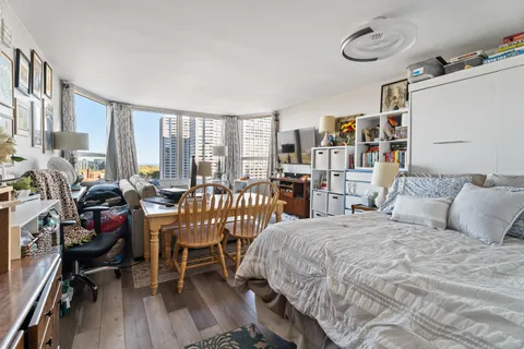 a bedroom with a bed a large window and book shelf