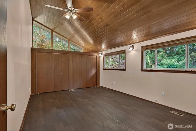 an empty room with windows and ceiling fan