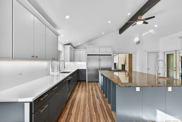 a large kitchen with kitchen island a large counter space wooden floor and stainless steel appliances