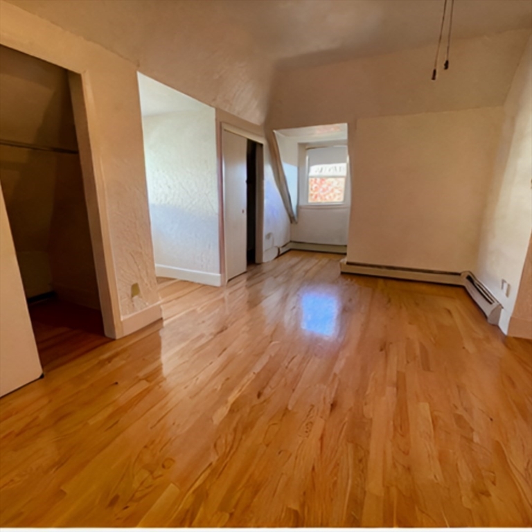 92 Thurston Street, Unit 3 Somerville, MA 02145 - Photo 3 of 10 a view of an empty room with wooden floor and a window