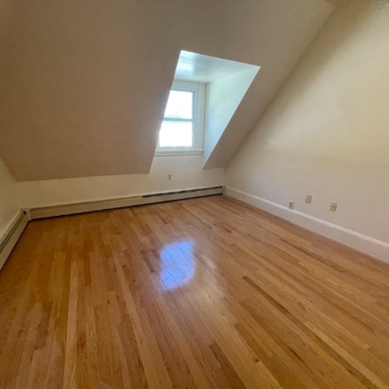 92 Thurston Street, Unit 3 Somerville, MA 02145 - Photo 5 of 10 an empty room with wooden floor and windows
