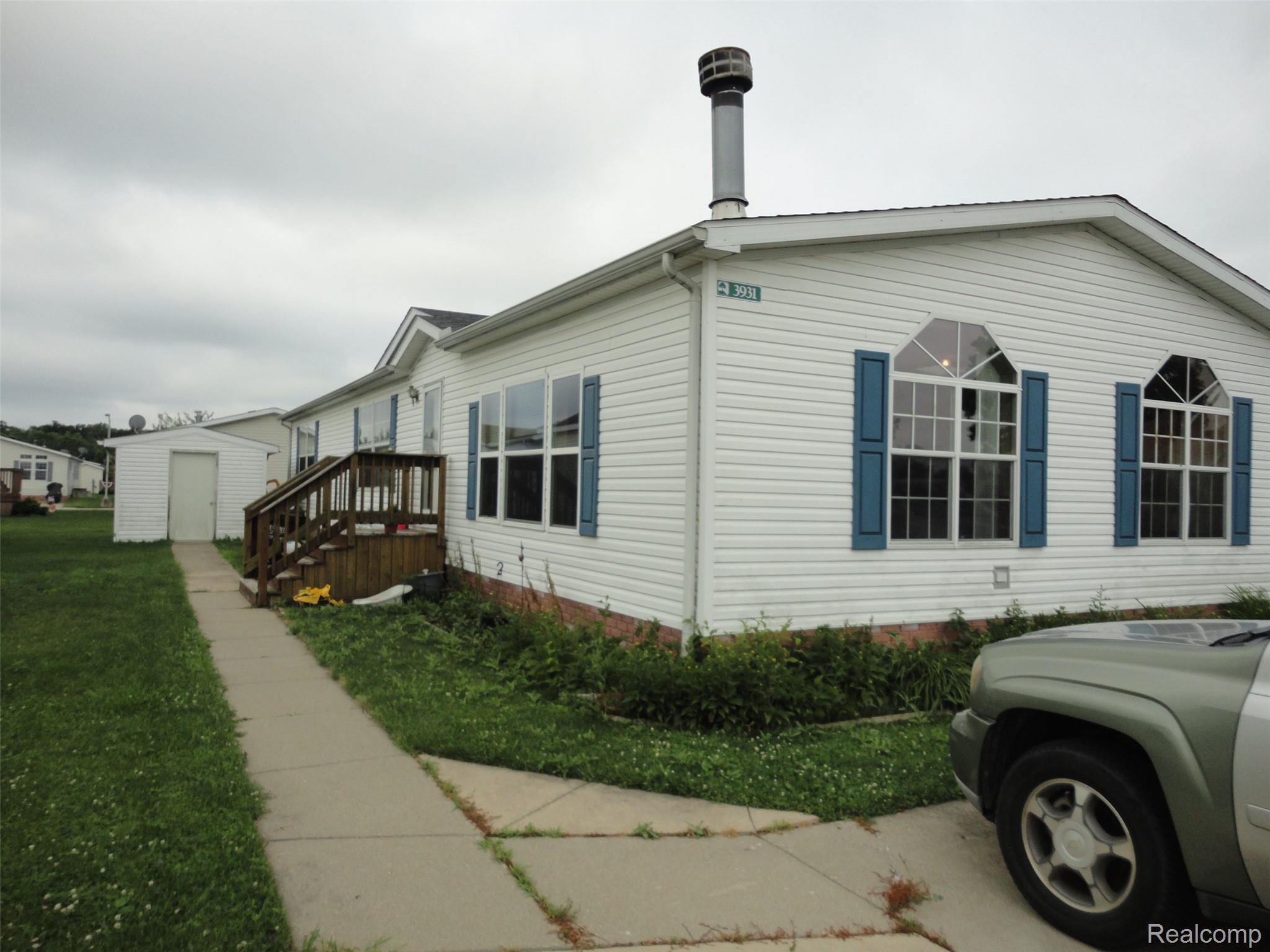 5931 Megans Ridge Monroe, MI 48161 - Photo 1 of 13 White siding exterior with blue window shutters, two arched transom windows, and a front entry deck with wood railing