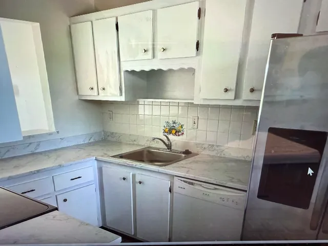 a kitchen with white cabinets and sink