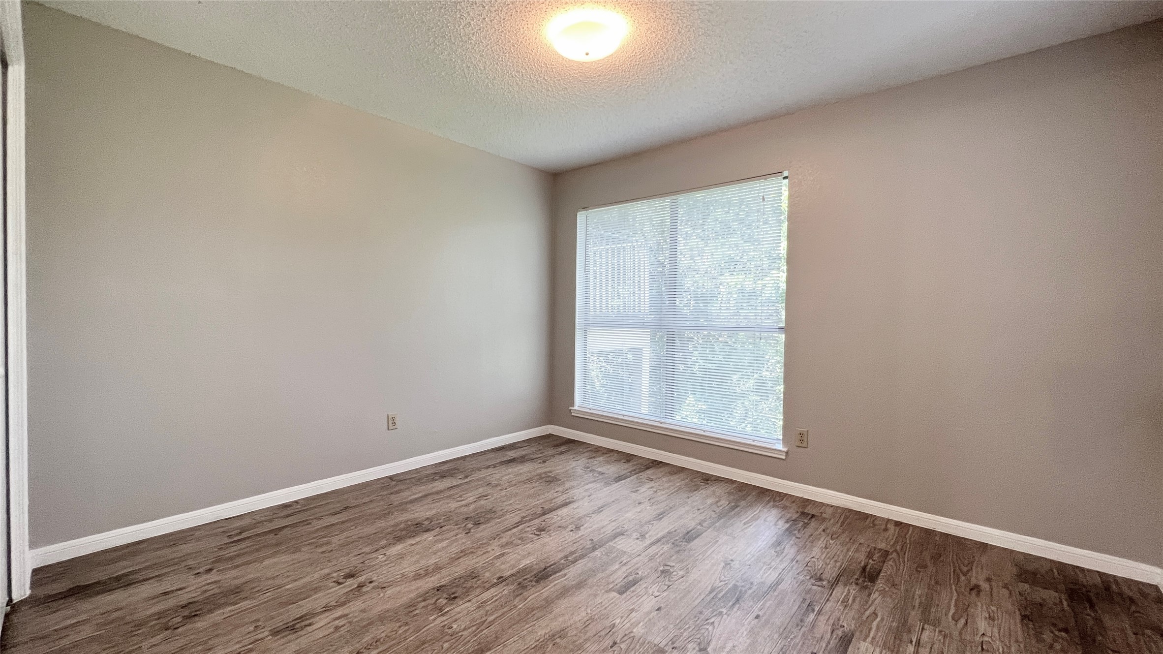 9201 Simmons Road, Unit 117 Austin, TX 78759 - Photo 16 of 20 A well-lit room with resilient wood-look flooring and a generous window, offering a versatile space.