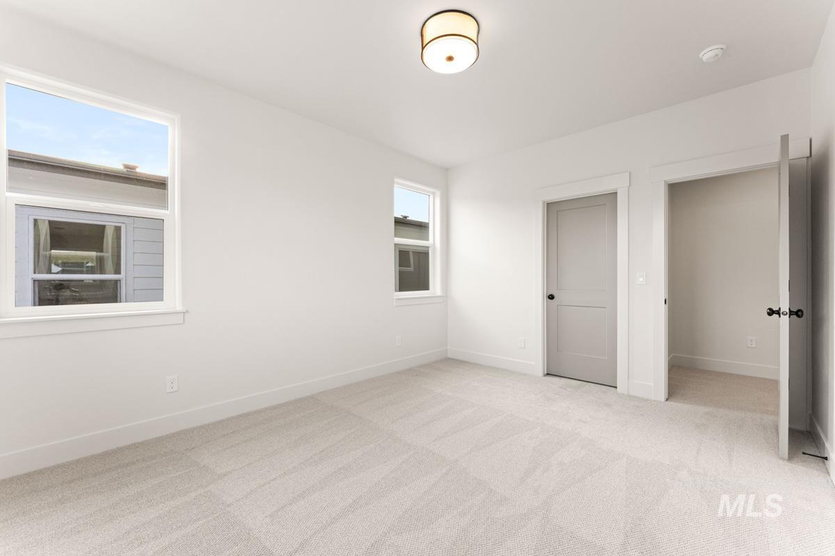 13338 North Spring Creek Way Boise, ID 83714 - Photo 31 of 46 Bright room featuring two windows, light-toned carpeting, white walls, and a contemporary flush mount ceiling light