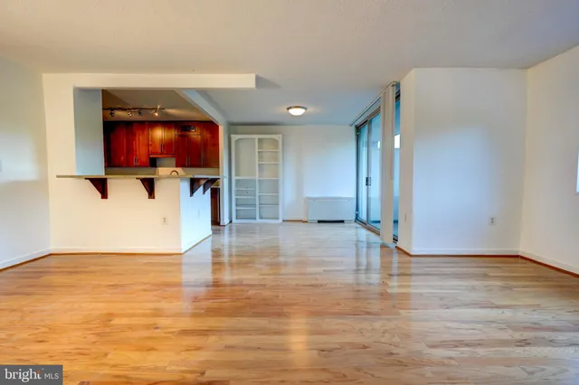 a view of empty room with wooden floor and a window