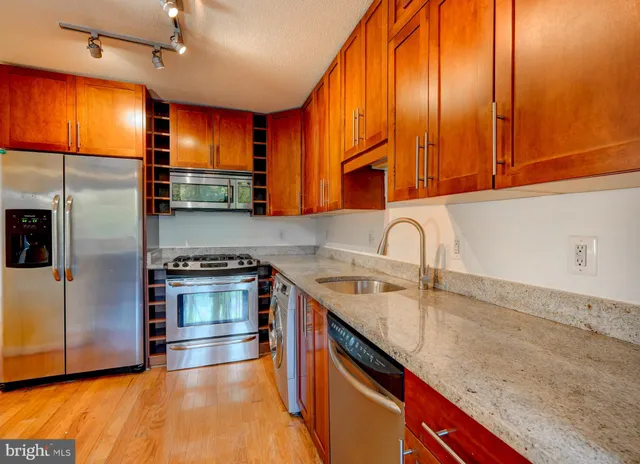 a kitchen with stainless steel appliances granite countertop a sink a stove and a refrigerator