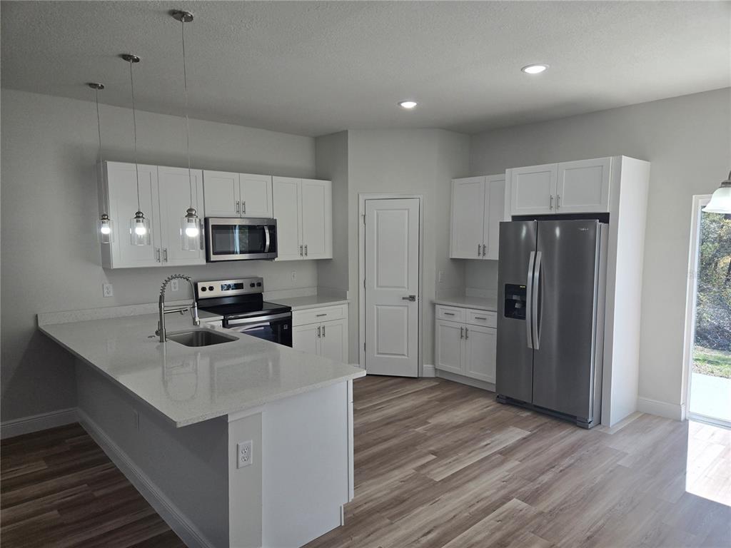 2644 Southwest 162nd Street Road Ocala, FL 34473 - Photo 15 of 47 a kitchen with a refrigerator a stove top oven and wooden floor