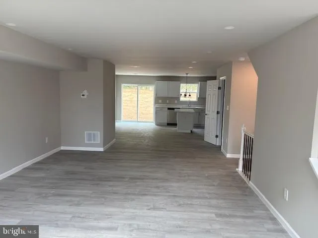 a view of a hallway with wooden floor and a living room