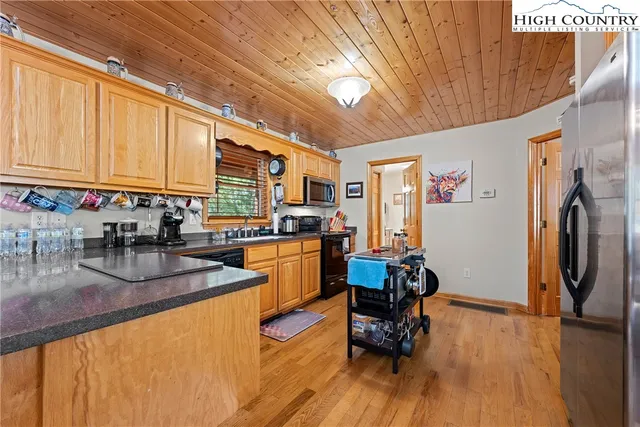 a kitchen with stainless steel appliances granite countertop a stove a refrigerator a sink dishwasher and wooden cabinets with wooden floor