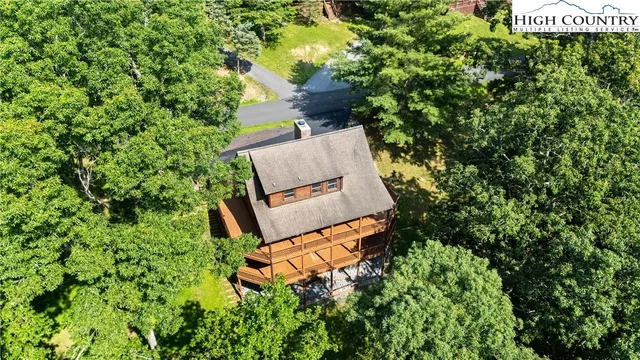 an aerial view of a house with a yard and trees all around