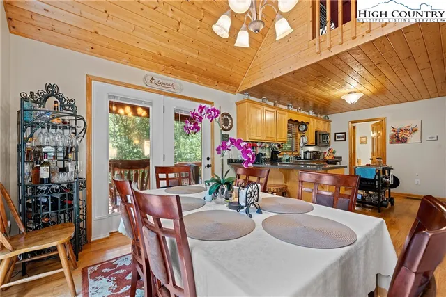 a kitchen with stainless steel appliances granite countertop a stove top oven a sink dishwasher a dining table and chairs with wooden floor