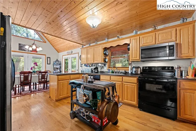 a kitchen with stainless steel appliances granite countertop a refrigerator a sink dishwasher a stove and white countertops with wooden floor