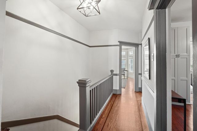 a view of a hallway with wooden floor and staircase