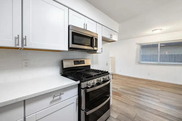 a kitchen with stainless steel appliances a stove microwave and sink