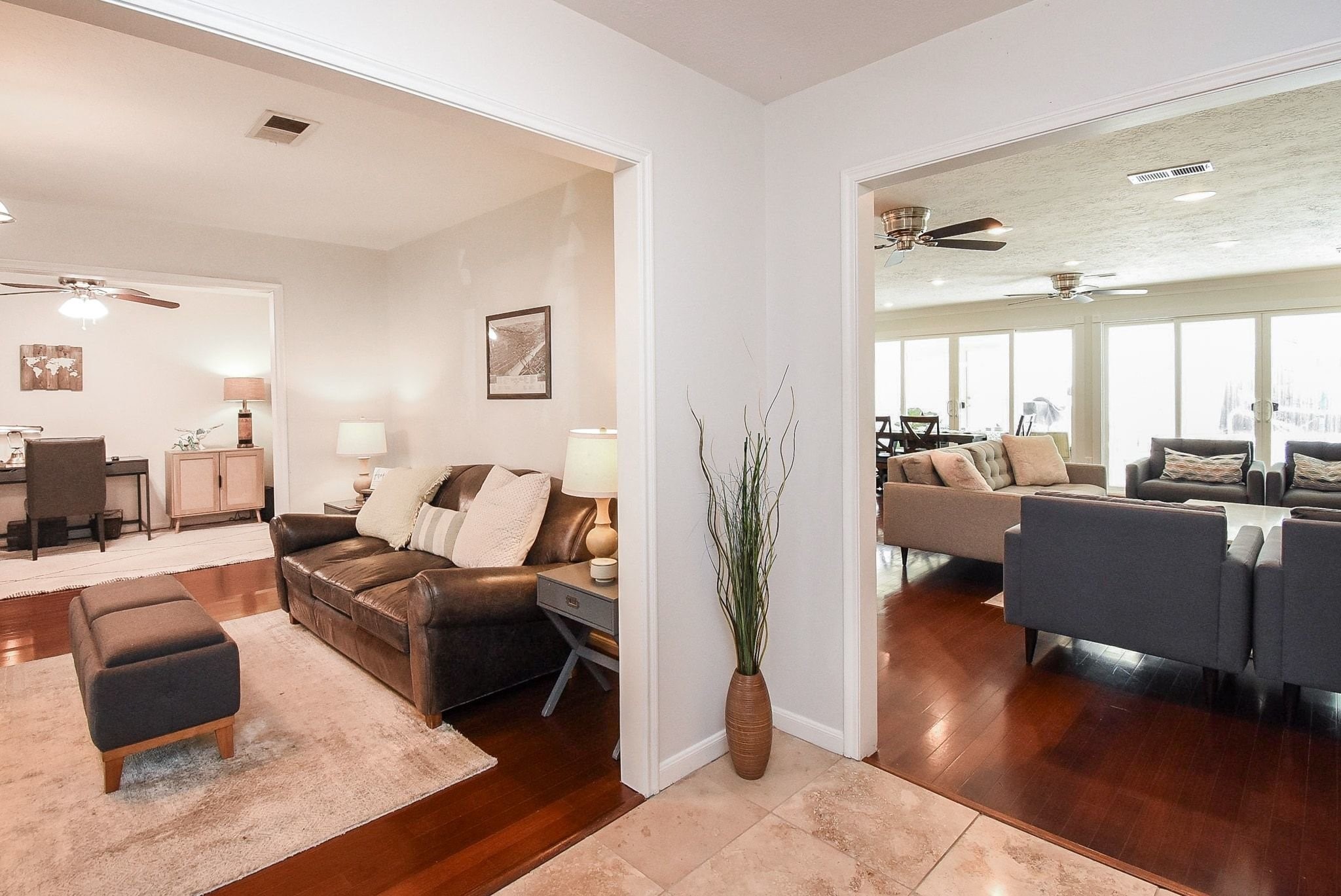 2930 Kevin Lane Houston, TX 77080 - Photo 17 of 50 This photo showcases a spacious, open living area with a cozy seating arrangement and ample natural light. The room features warm wood flooring, ceiling fans, and a neutral color palette, creating a welcoming and comfortable atmosphere.