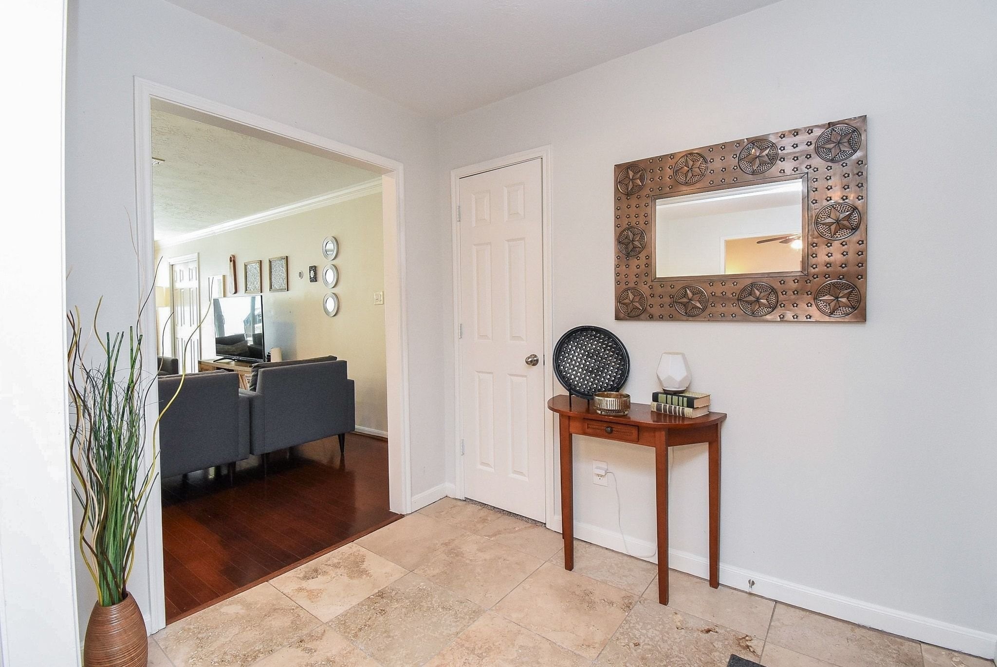 2930 Kevin Lane Houston, TX 77080 - Photo 18 of 50 This photo features a welcoming entryway with light tile flooring. The hallway leads to a cozy living area with hardwood floors and stylish decor.