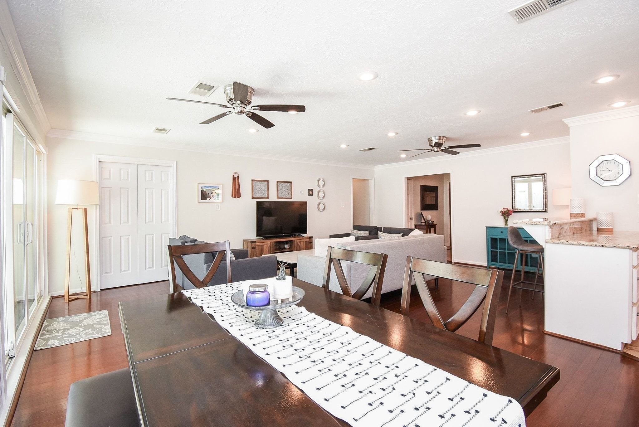2930 Kevin Lane Houston, TX 77080 - Photo 28 of 50 This bright, open-concept living space features hardwood floors, recessed lighting, and ceiling fans. It includes a dining area and a kitchen with a breakfast bar. Large sliding doors provide natural light, creating a welcoming atmosphere.