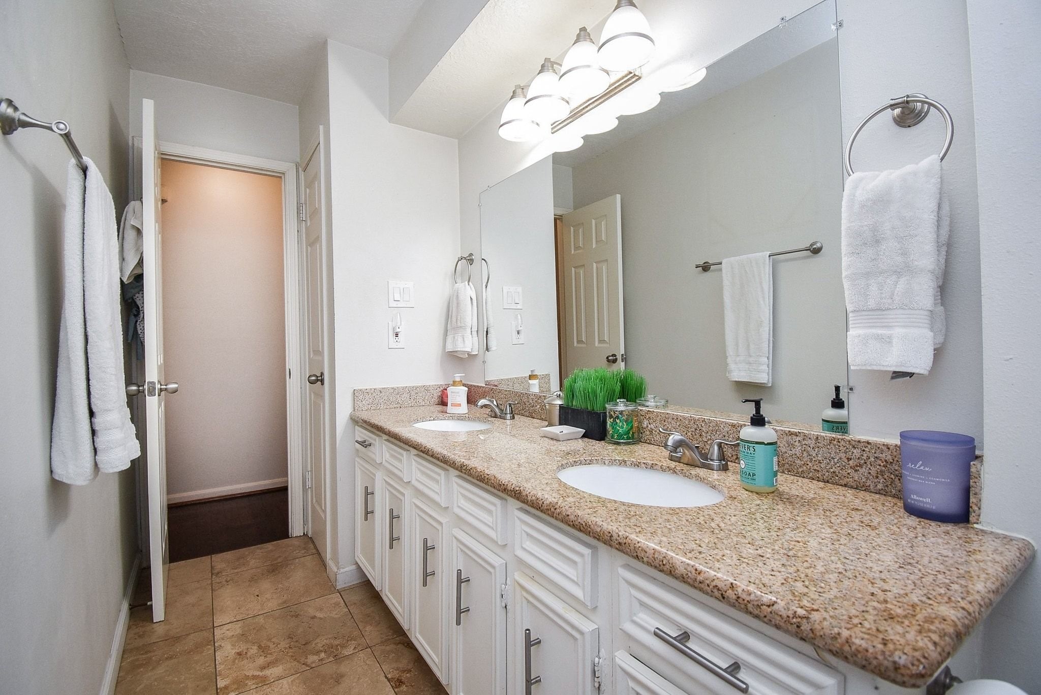 2930 Kevin Lane Houston, TX 77080 - Photo 36 of 50 This bathroom features dual sinks with a granite countertop, ample cabinet storage, and large mirrors. The neutral tile flooring and bright lighting create a clean, inviting atmosphere.