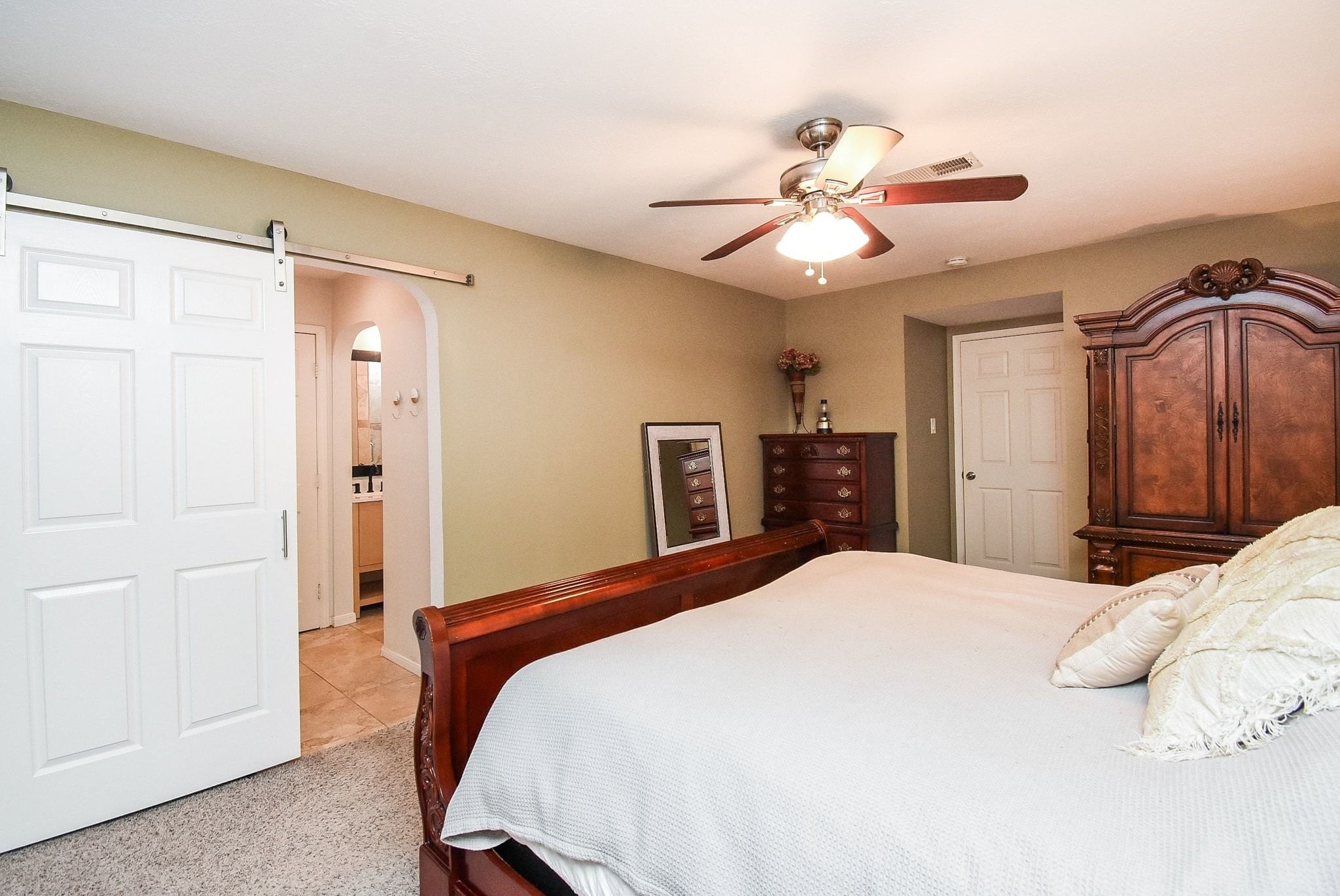 2930 Kevin Lane Houston, TX 77080 - Photo 45 of 50 This warm bedroom features a ceiling fan, plush carpet, and a sliding barn door ensuite bathroom, enhancing convenience and style.
