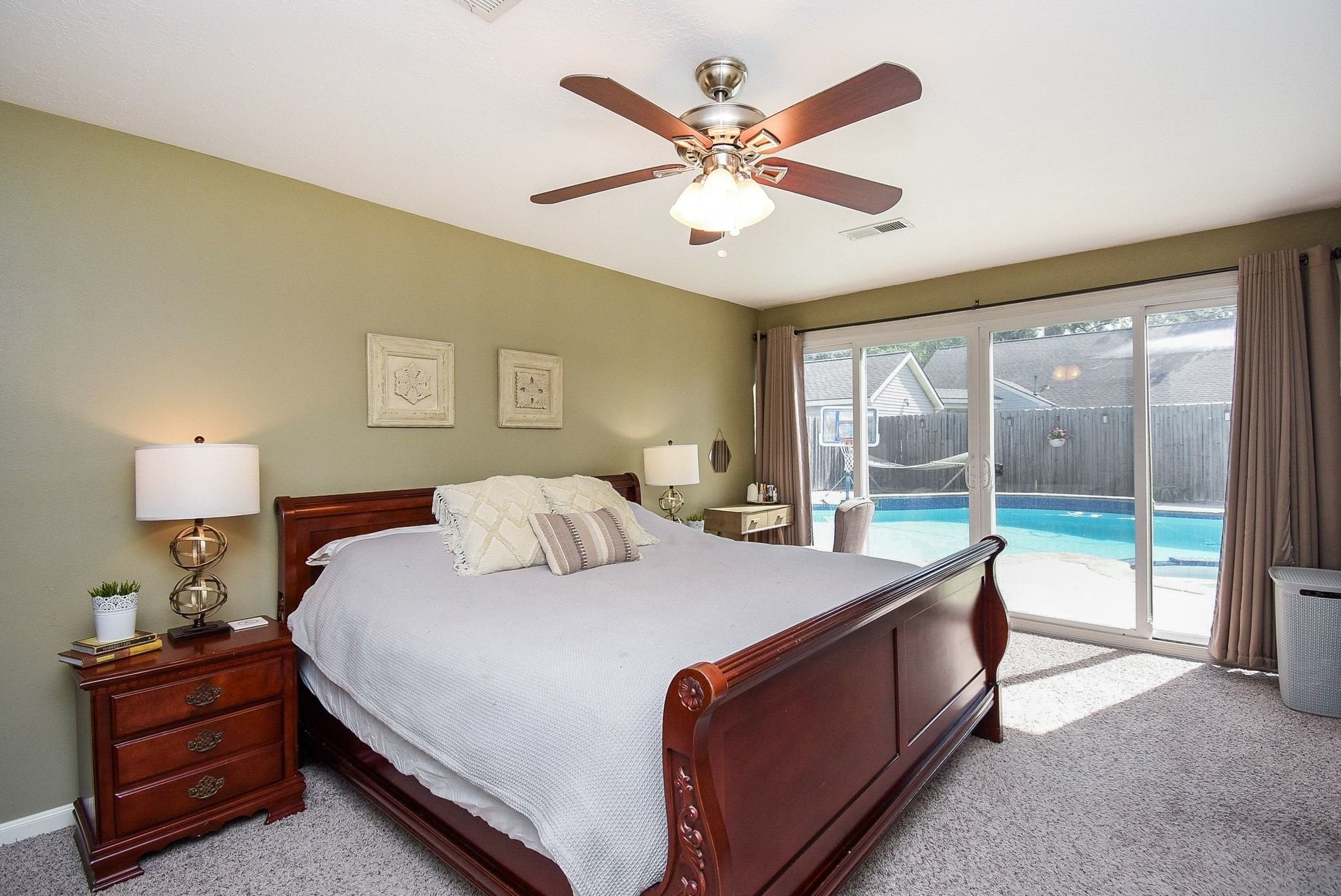 2930 Kevin Lane Houston, TX 77080 - Photo 46 of 50 Spacious bedroom with a warm color palette, featuring a large bed, ceiling fan, and sliding glass doors leading to a backyard with a pool.