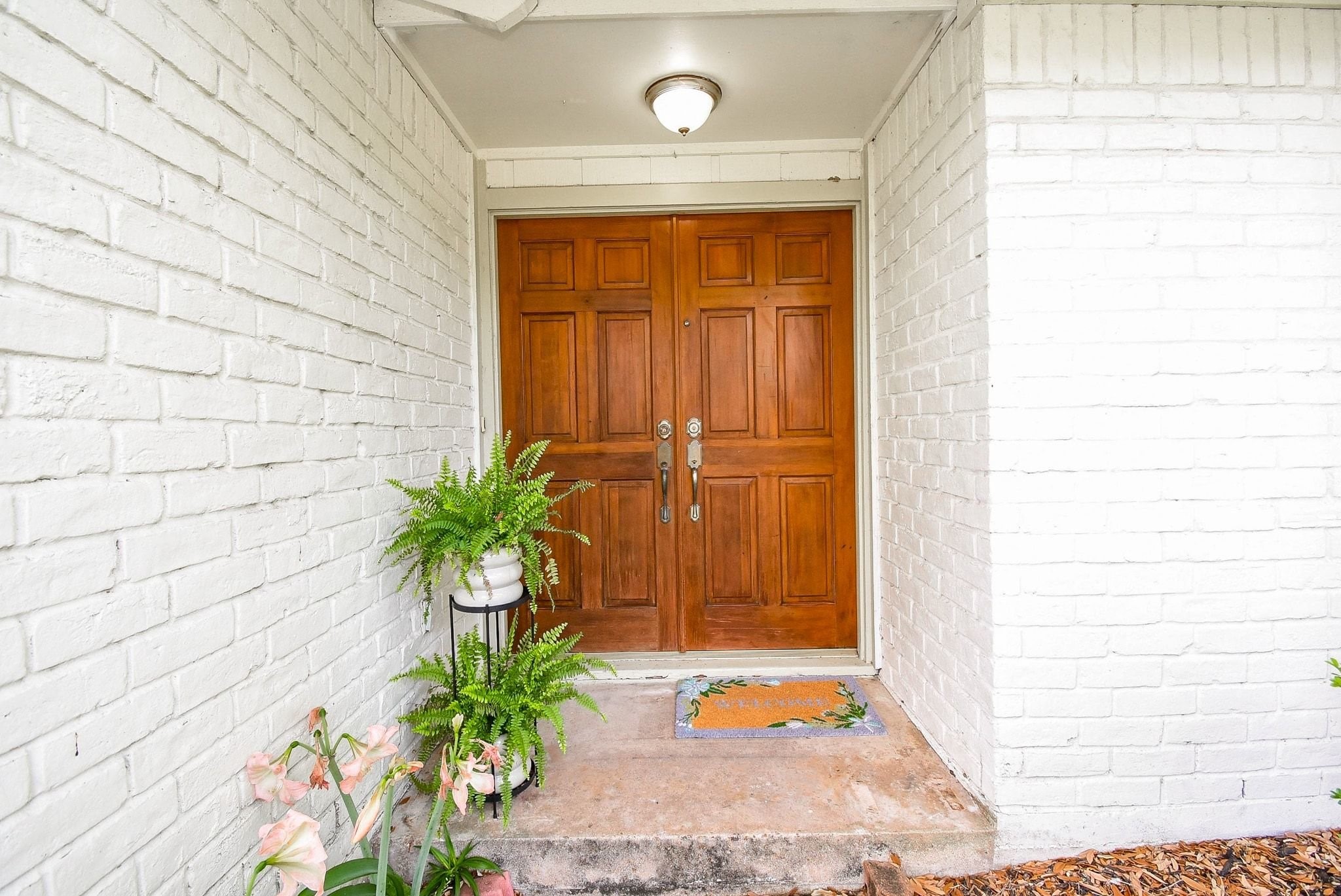 2930 Kevin Lane Houston, TX 77080 - Photo 8 of 50 This inviting entryway features a sturdy wooden door framed by white brick walls. The space is creating a charming first impression for visitors.