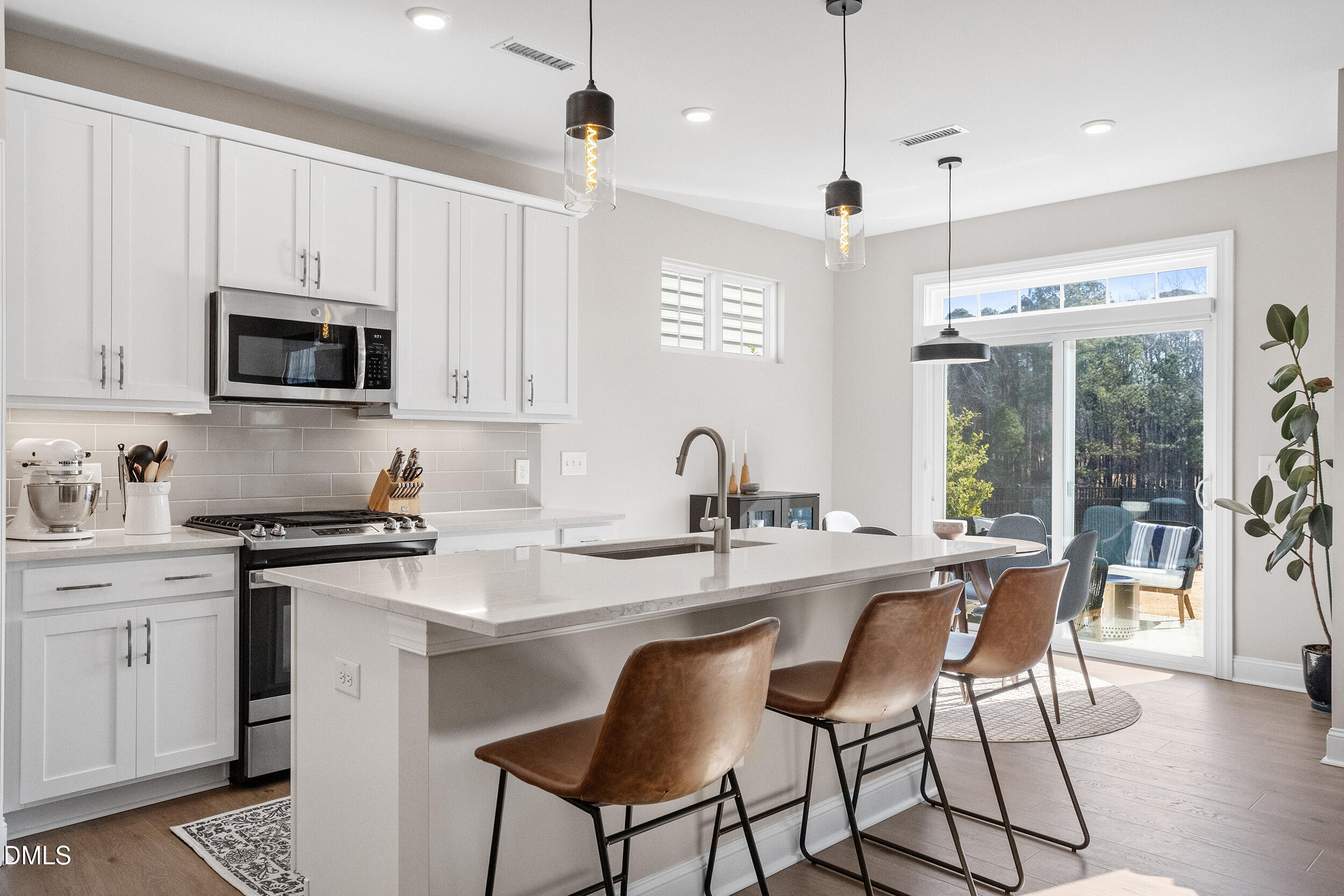 1602 Farm Pond Trail Durham, NC 27703 - Photo 10 of 43 a kitchen with stainless steel appliances granite countertop a stove a sink a refrigerator a dining table and chairs with wooden floor