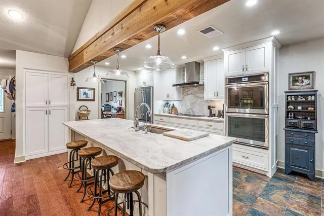a kitchen with stainless steel appliances kitchen island granite countertop a kitchen island and chairs in it